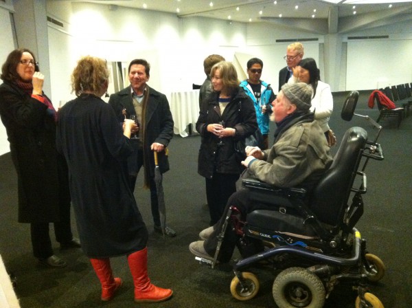 Jo Verrent speaking with audience members following her forum in Adelaide. Jo is wearing red boots, standing with her back to the camera.