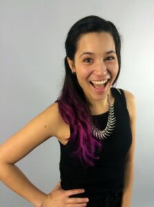 A colour photograph of Sophi Li. She has long, straight black hair with purple tips. She is waring a black top and a silver spiky necklace.