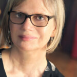 A photograph of Gaele Sobott, a blond haired woman wearing dark-rimmed glasses in modern style.