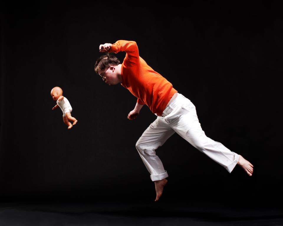 Lorcan jumping through the air with a doll. in colour, Photo credit Katie Pashley.